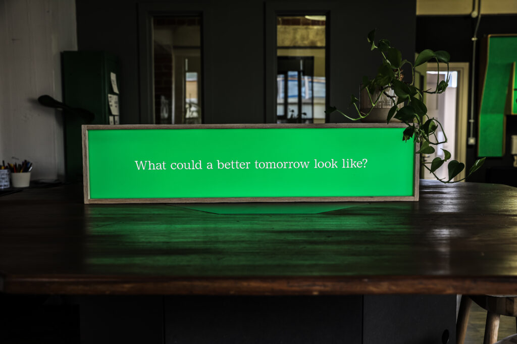 Green Lightbox placed on a table that reads "What could a better tomorrow look like?"